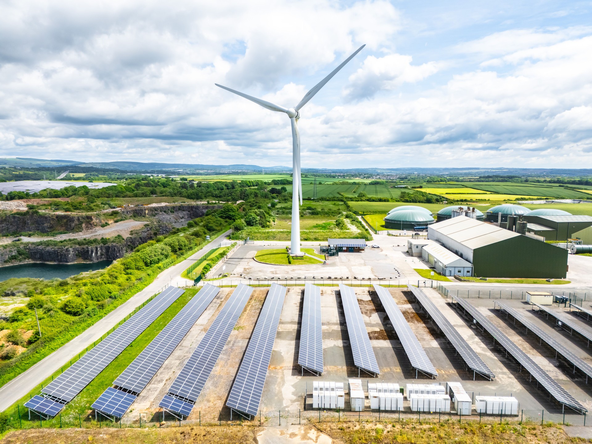 Aerial view of solar panels and Wind turbines on green field at suburb in sunny day